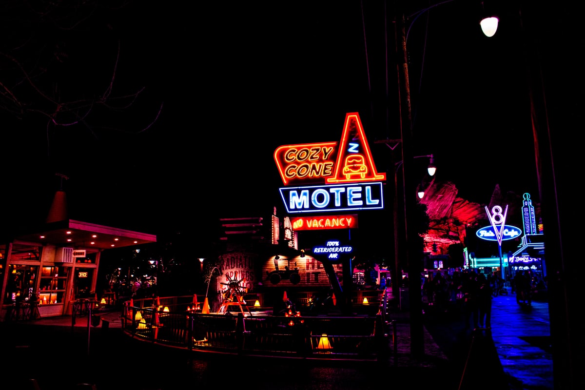 The Cozy Cone Motel sign glowing orange and blue at night.