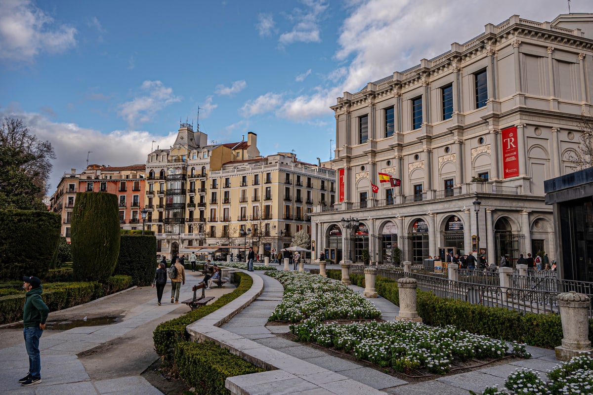 Manicured gardens and white flowers leading to the Teatro Real in Madrid.