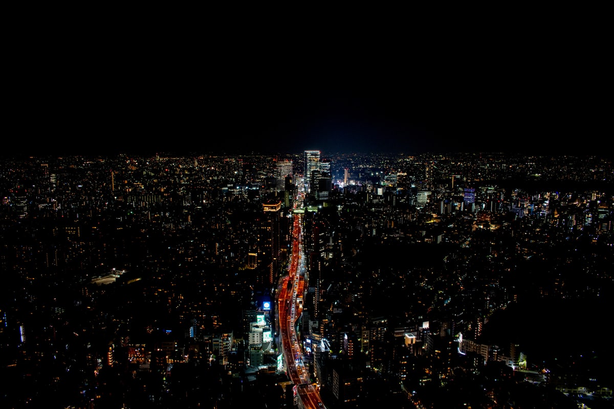 A highway of light cuts through the endless city grid of Tokyo at night.