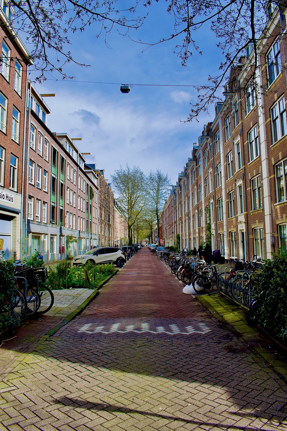 A red-brick street lined with parked bikes and apartment buildings.