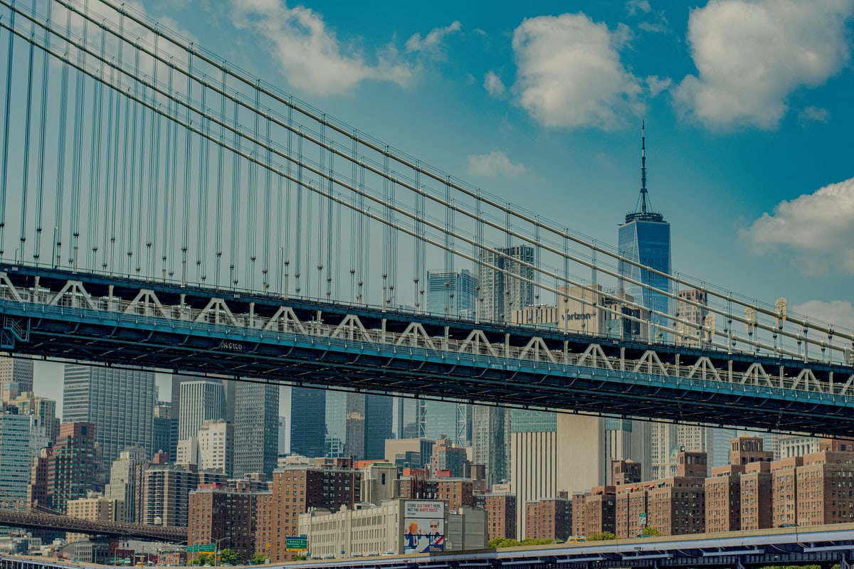 The Manhattan Bridge spans the frame with One World Trade Center beyond.