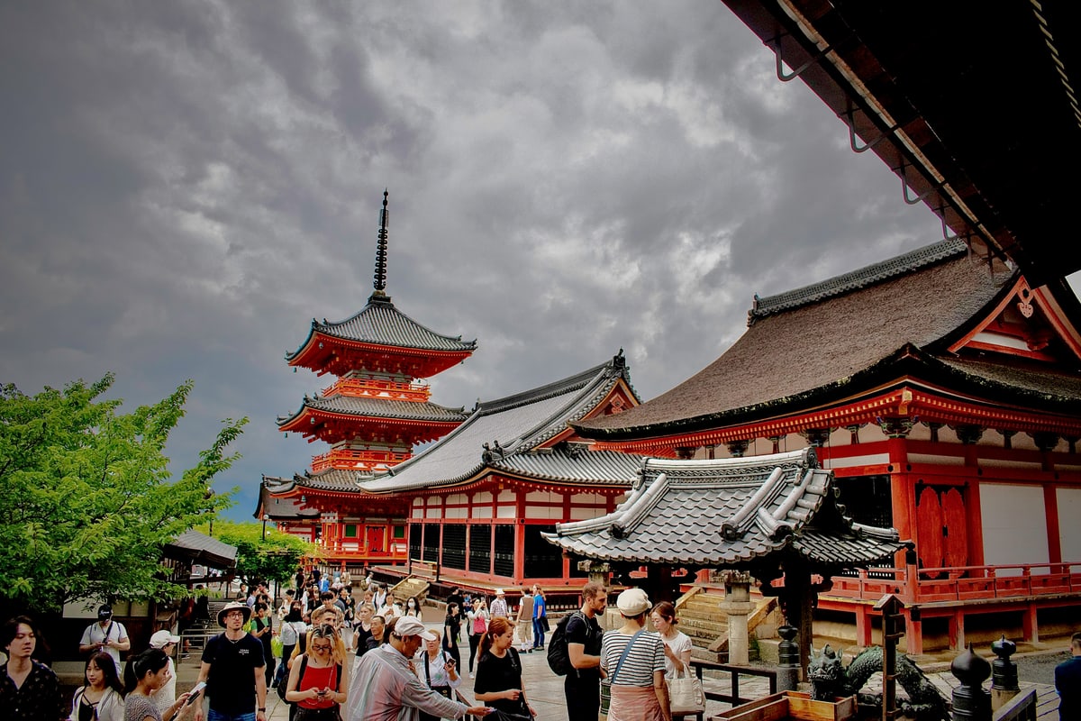 The red three-story pagoda and temple halls of Kiyomizu-dera crowded with visitors.