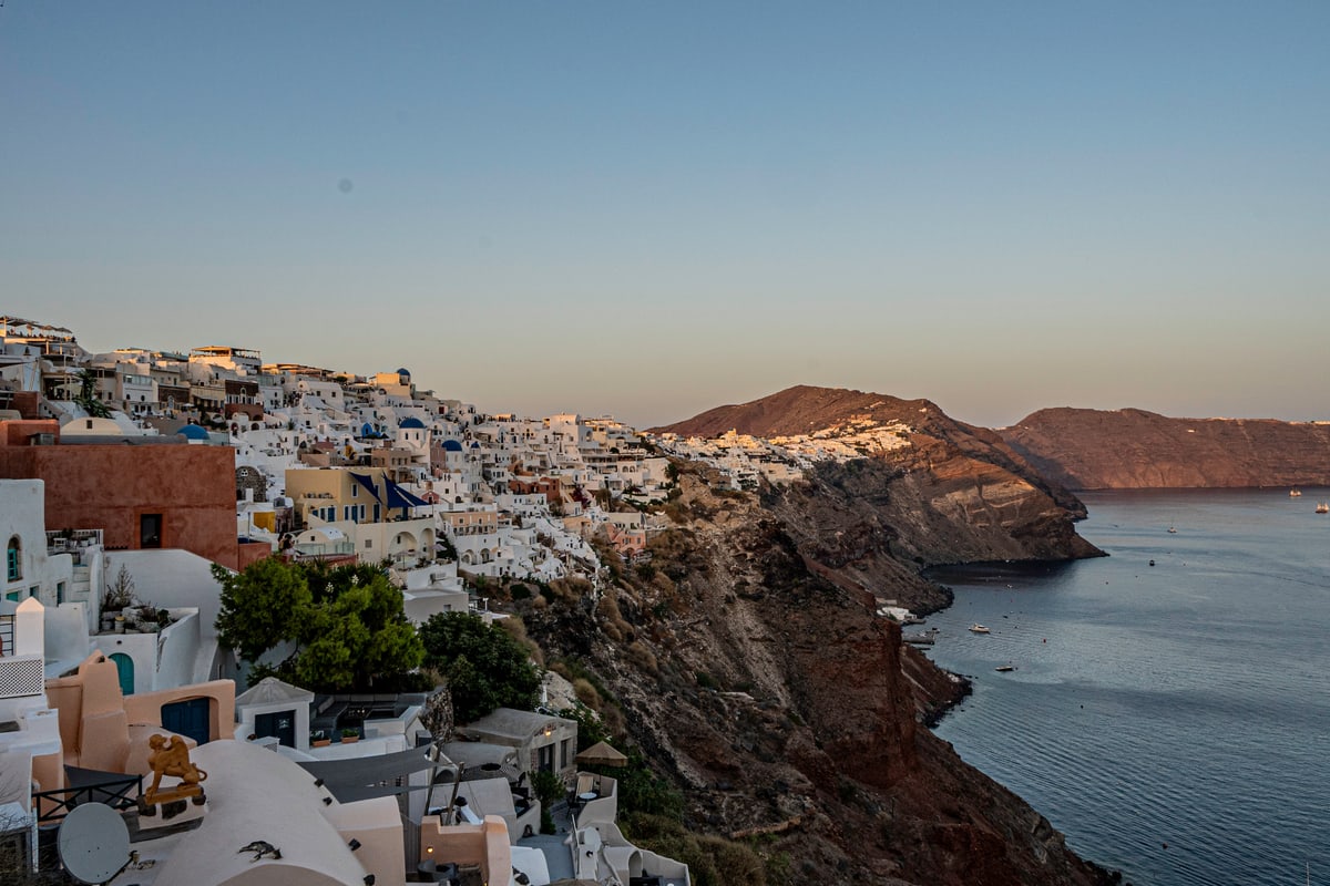 Whitewashed houses spill down the volcanic cliffs of Santorini above the sea.