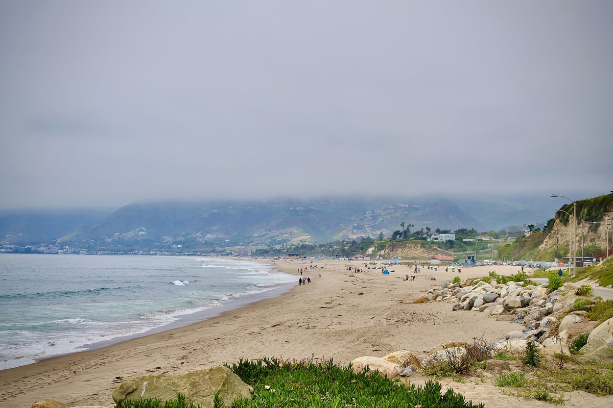 A wide beach under a low marine layer with hills fading into the haze.