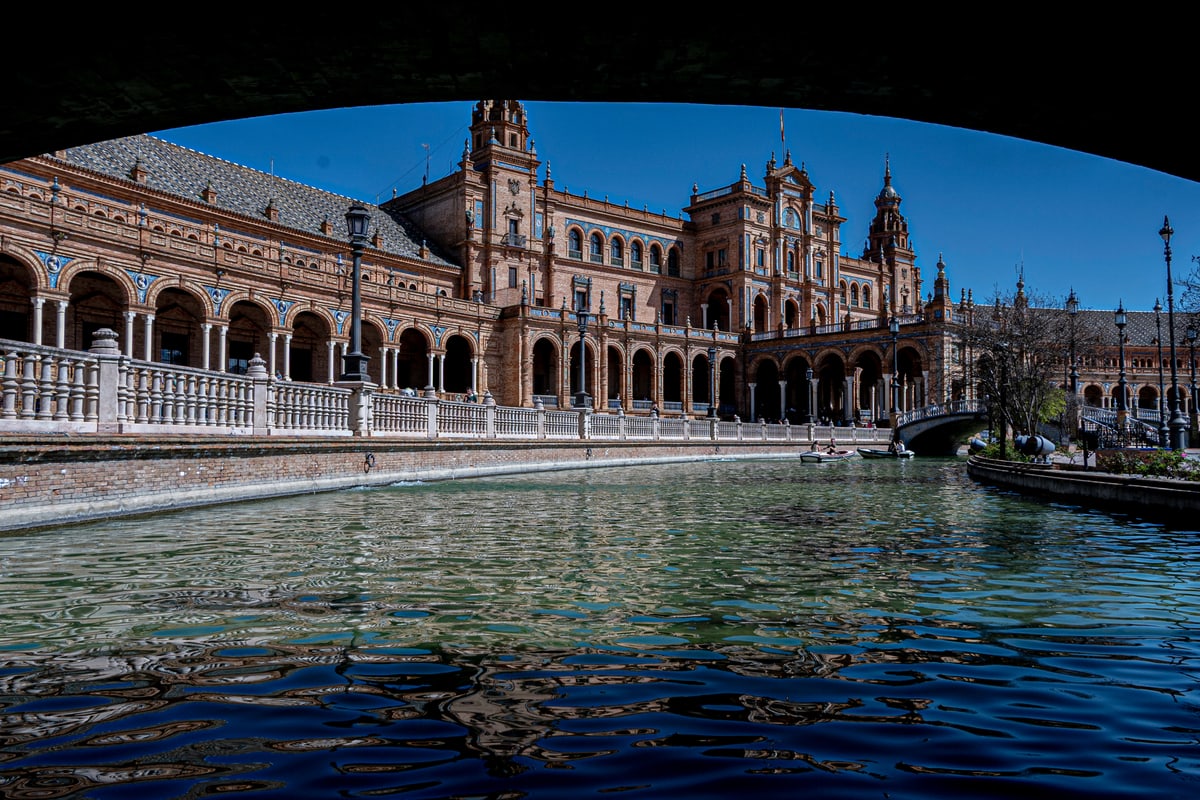 The curved arcades and towers of Plaza de España in Seville, seen across the canal.