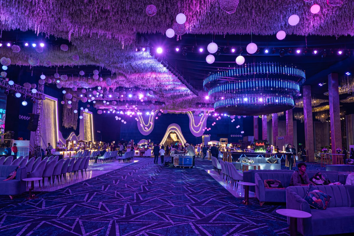 Rows of lounge seating under a canopy of hanging flowers and glowing orbs.