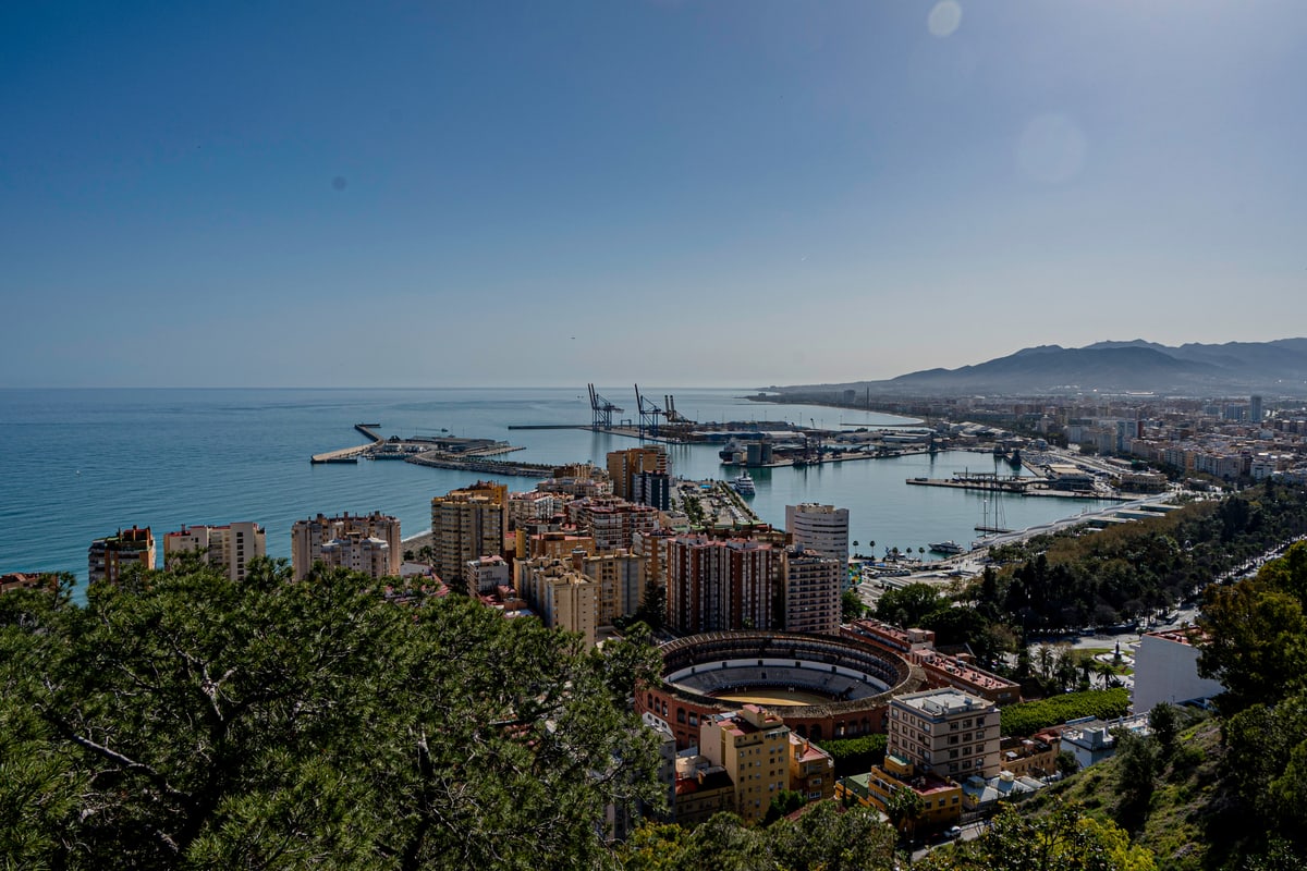 Málaga's harbor, bullring and coastline seen from a hilltop.